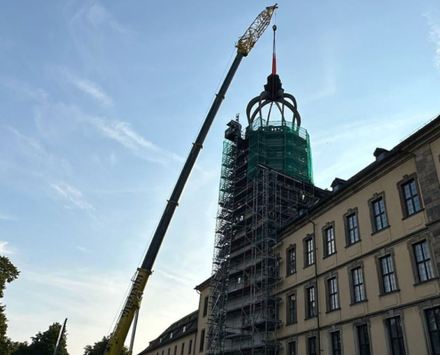 Per Kran wird die neue Stahlhaube auf dem Schlossturm positioniert
