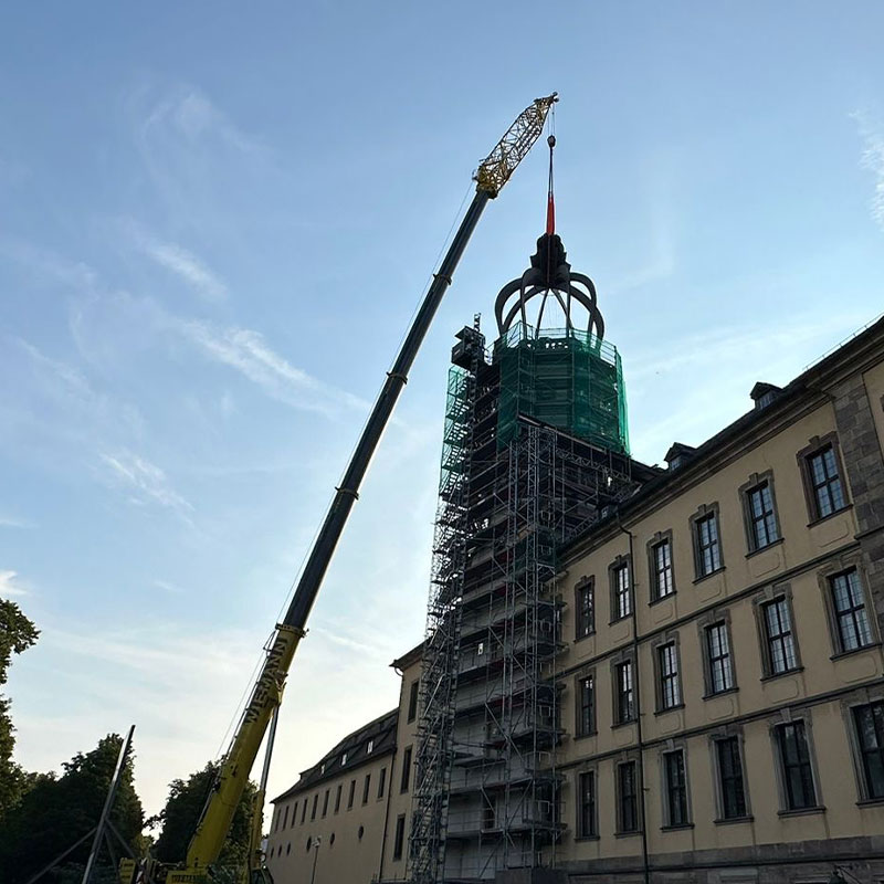 Per Kran wird die neue Stahlhaube auf dem Schlossturm positioniert
