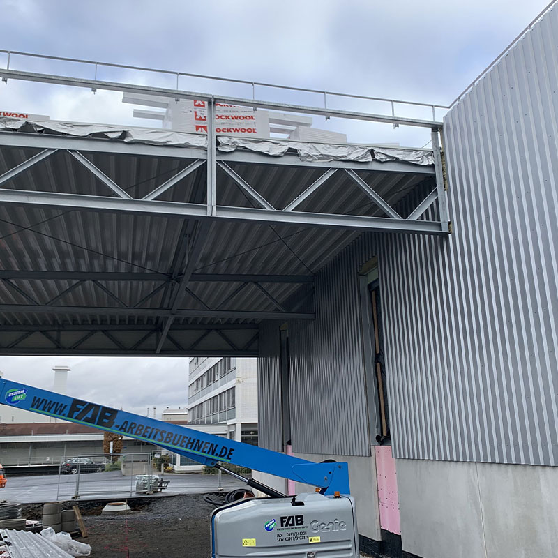 Auskragende Stahlkonstruktion des Hallenvordachs während der Montage am Werk von Wagner Fahrzeugteile mit dem Hubsteiger