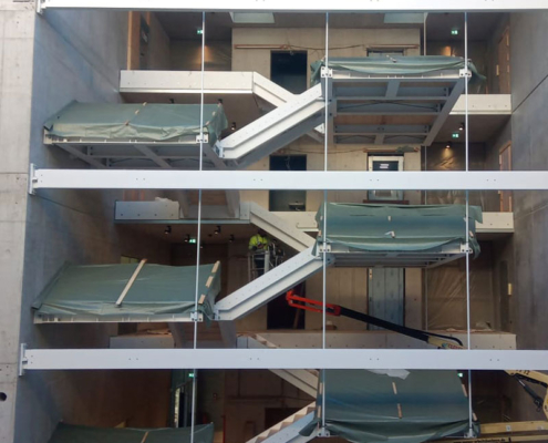 Blick von der Seite auf die schwebende Stahltreppe während der Montage im Bürogebäude Valley One24 in Stuttgart