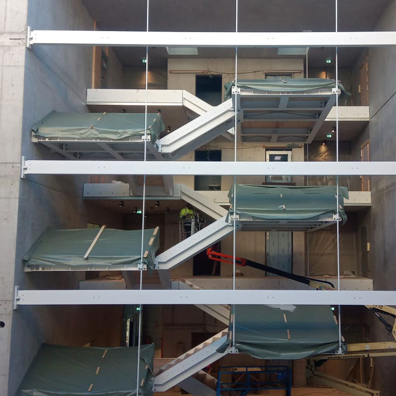 Blick von der Seite auf die schwebende Stahltreppe während der Montage im Bürogebäude Valley One24 in Stuttgart