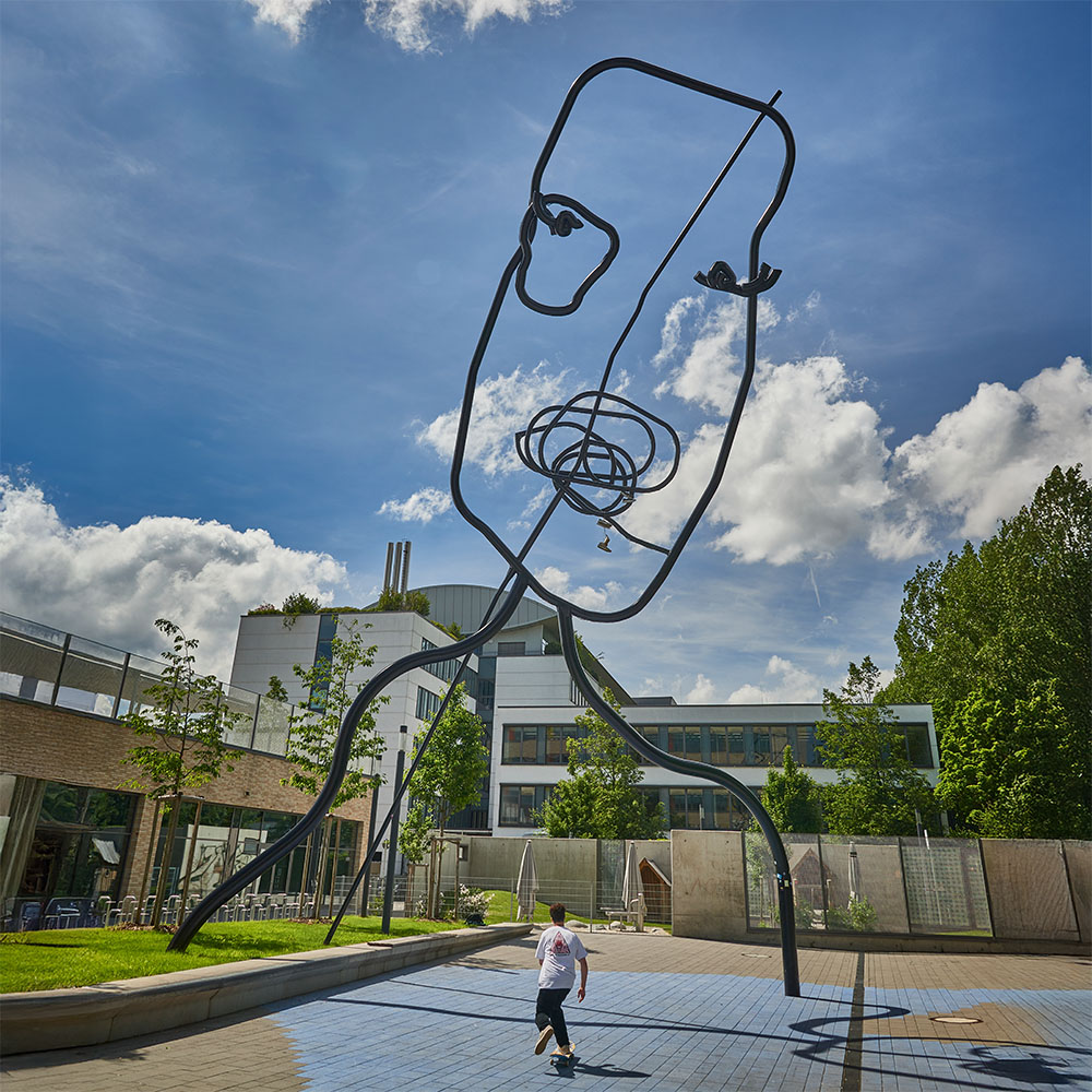 Die Skulptur "I See A Face. Do You See A Face" von Flaka Haliti mit einem Skateboarder davor fahrend